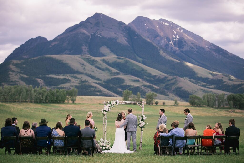 A stunning outdoor wedding ceremony at Sage Lodge, with the couple exchanging vows against the breathtaking backdrop of Paradise Valley and the Absaroka Mountains.